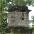 Gedenkstein im Friedenspark Gedenkstein aus Stein mit Inschrift, umgeben von Bäumen im Friedenspark, erinnert an historische Ereignisse.