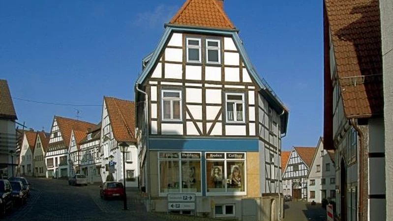 Fachwerkhäuser säumen den gepflasterten Langen Steinweg, blauer Himmel im Hintergrund.