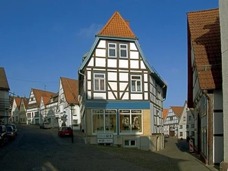 Blick in den Langen Steinweg / Kuhstraße Fachwerkhäuser säumen den gepflasterten Langen Steinweg, blauer Himmel im Hintergrund.