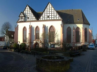 Klosterkirche Blomberg mit gotischen Fenstern, Fachwerk und einem Brunnen im Vordergrund bei klarem Himmel.