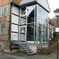 Stadtarchiv Modernes Glaseingangsportal mit Metalltreppe an einem historischen Fachwerkgebäude in städtischer Umgebung.