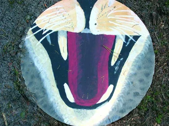 Der große Lebens-Kreis-Lauf Runder Stein mit farbenfroher, abstrakter Bemalung, die ein Tiermaul mit gespitzten Krallen darstellt.