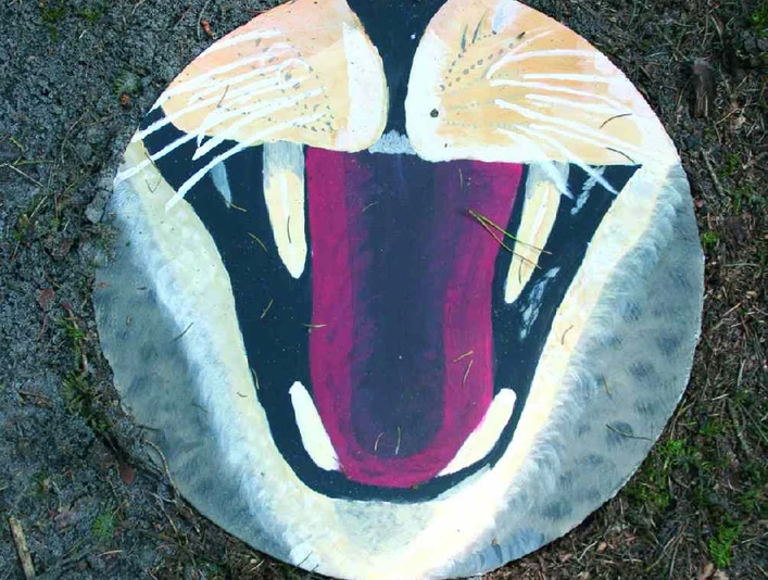 Der große Lebens-Kreis-Lauf Runder Stein mit farbenfroher, abstrakter Bemalung, die ein Tiermaul mit gespitzten Krallen darstellt.