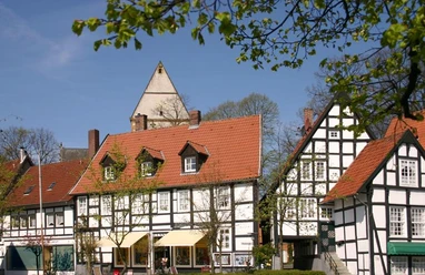 Fachwerkhäuser in einer malerischen Altstadt mit blauem Himmel und grünen Bäumen im Frühling.