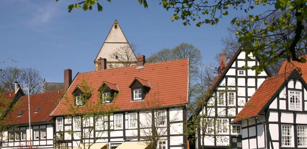 Halle Westfalen, Kirchplatz "Haller Herz" Fachwerkhäuser in einer malerischen Altstadt mit blauem Himmel und grünen Bäumen im Frühling.