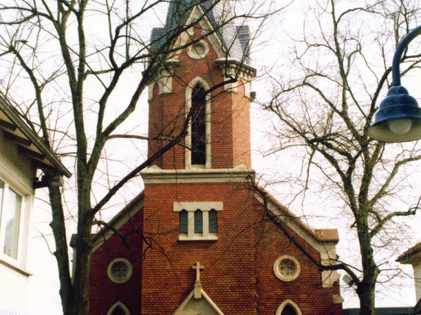 Bürgerhaus am Clara-Ernst-Platz Rotes Backsteinhaus mit Turm und Spitzdach, umgeben von Bäumen, im belebten Stadtteil.