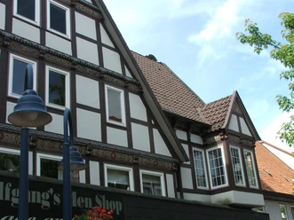 Fachwerkhaus mit aufwendigen Verzierungen, Schrägdach und historischen Fenstern unter blauem Himmel.