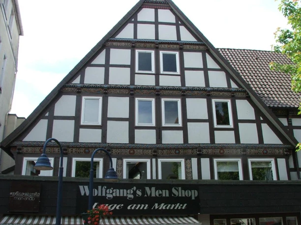 Ackerbürgerhaus Lange Str. 64 Fachwerkgebäude mit schwarz-weißer Fassade und drei Dachfenstern, beherbergt "Wolfgang's Men Shop".