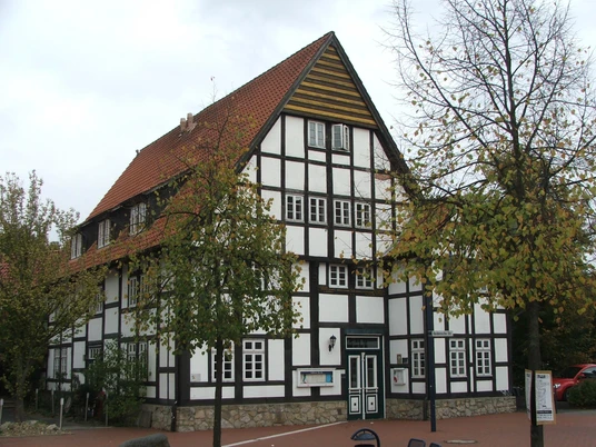 Haus Brinkmann Fachwerkhaus mit roten Ziegeldach und auffälligen Giebelmustern, umgeben von herbstlichen Bäumen.