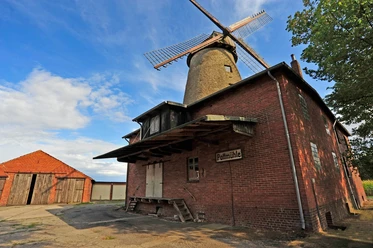 Pottmühle Petershagen Historische Pottmühle aus rotem Backstein mit hölzernen Flügeln und angrenzendem Schuppen.