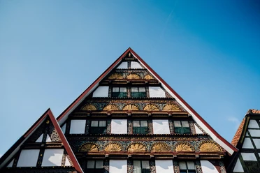 Fassade historische Altstadt Dreiecksgiebel mit reich verzierten Fachwerkelementen einer historischen Altstadtfassade unter blauem Himmel.