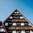 Fassade historische Altstadt Dreiecksgiebel mit reich verzierten Fachwerkelementen einer historischen Altstadtfassade unter blauem Himmel.