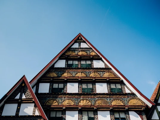 Fassade historische Altstadt Dreiecksgiebel mit reich verzierten Fachwerkelementen einer historischen Altstadtfassade unter blauem Himmel.