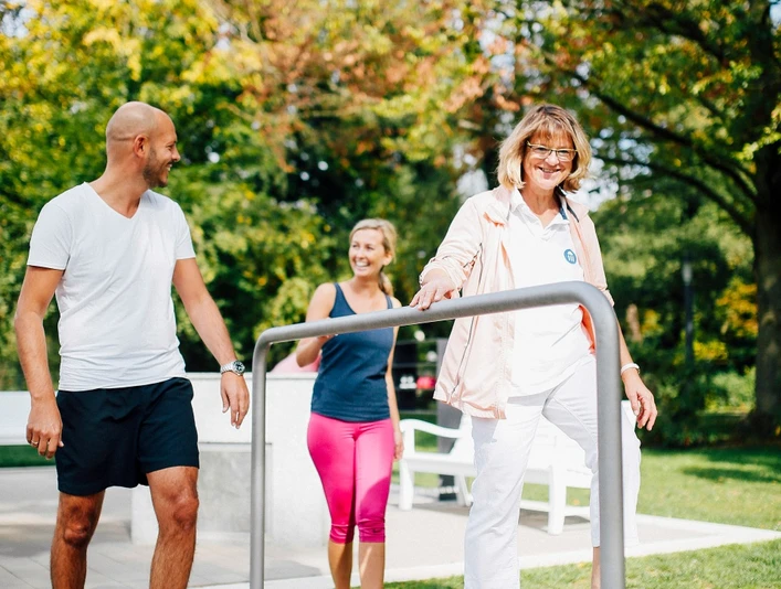 Personen spazieren fröhlich auf dem Balancepfad des Kurparks Bad Salzuflen an einem sonnigen Tag.