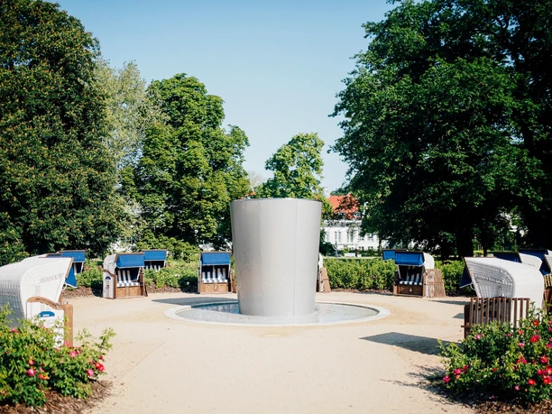 Staatsbad Salzuflen - Strandkörbe am Solestrand Strandkörbe umringen einen modernen Springbrunnen, eingebettet in einen grünen Park voller Bäume.