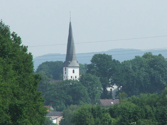 Die Dorfkirche Heiden mit ihrem spitzem Turm ist von üppigem Grün umgeben und durch Bäume eingebettet.