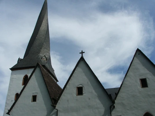 Dorfkirche Heiden Gothische Dorfkirche mit markantem schlanken Turm und drei Giebeln unter blauem Himmel.