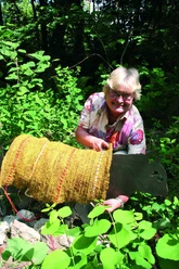 Sigrid Schröder Sigrid Schröder präsentiert eine große, goldene Skulptur inmitten üppiger, sommerlich grüner Natur.
