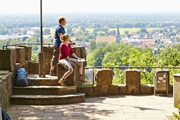 Schöne Aussicht in Hörstel Zwei Wanderer genießen von einer steinernen Plattform aus den weiten Blick über eine grüne Landschaft.
