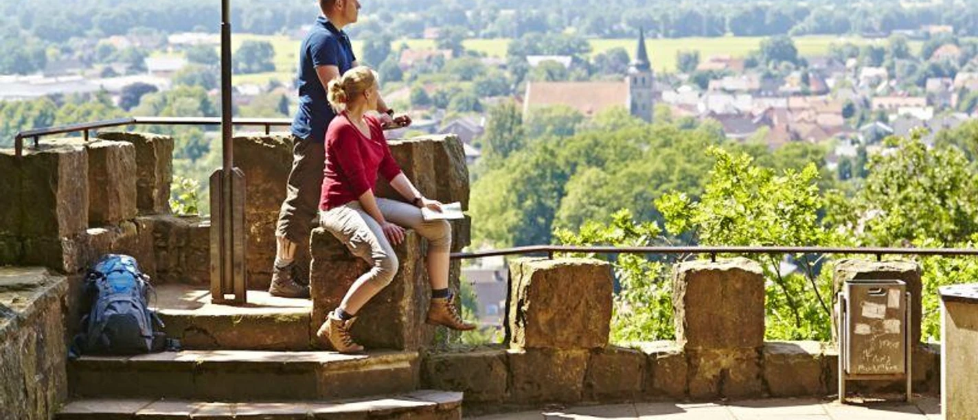 Schöne Aussicht in Hörstel Zwei Wanderer genießen von einer steinernen Plattform aus den weiten Blick über eine grüne Landschaft.