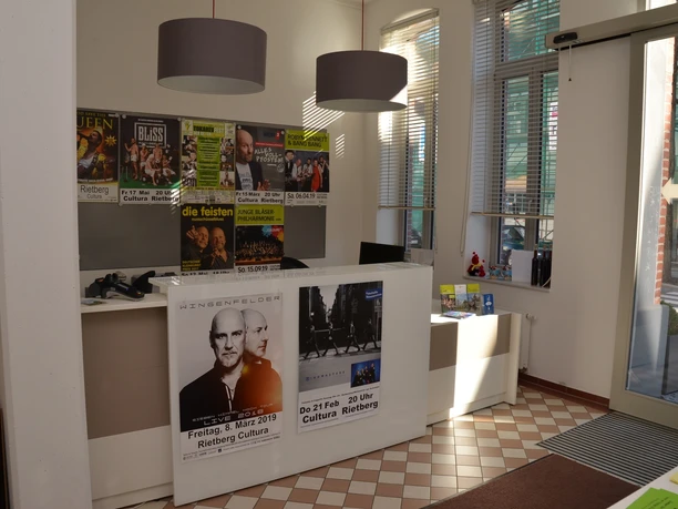 Innenraum Touristik Lichtdurchfluteter Ticketverkauf mit Kinopostern, modernem Empfang und großen, runden Lampen.