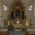 Barockes Kircheninterieur mit prächtigem Altar, Seitenaltären, Statuen und bunten Glasfenstern.