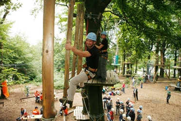 Kletterpark am Hermannsdenkmal Menschen in einem Kletterpark genießen Seilbahnen zwischen hohen Bäumen bei sonnigem Wetter.