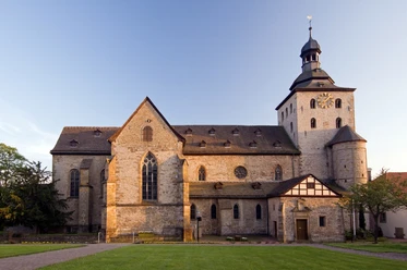 Romanische Kirche Eggeedom Neuenheerse mit markantem Turm, umgeben von grünem Rasen und Bäumen.