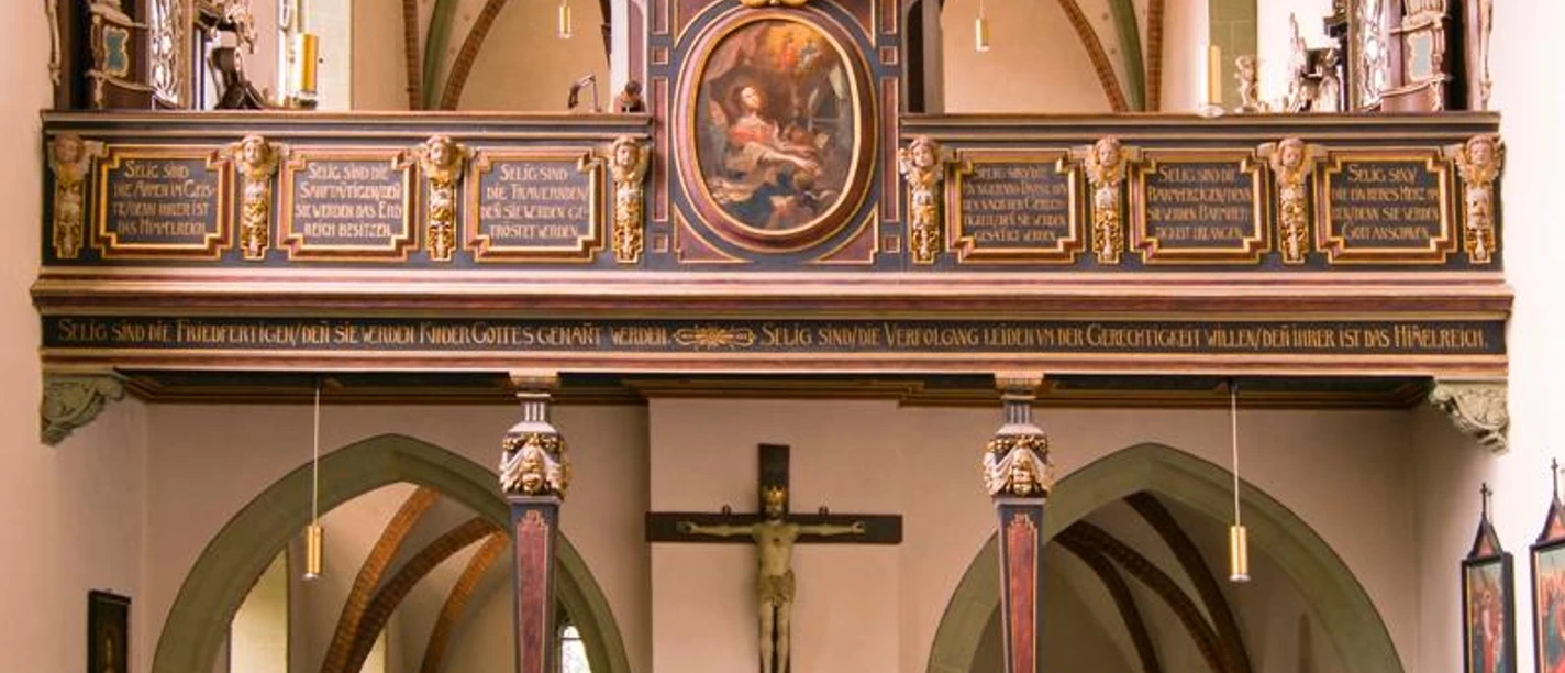 Innenraum der ehemaligen Klosterkirche mit prächtiger Orgel auf der Empore und schlichten Kirchenbänken.