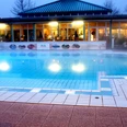 Abendstimmung in der Driburg Therme Die Driburg Therme beleuchtet sanft am Abend, mit einem klaren Außenpool und stimmungsvollen Lichtern.