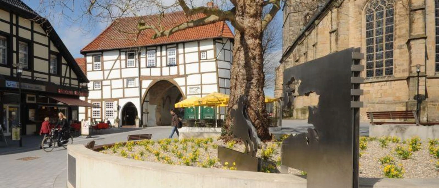 Ev. Stadtkirche Lengerich mit Römer / Friedensreiter Lengericher Stadtkirche mit modernem Römerdenkmal und historischem Fachwerkgebäude im Hintergrund.