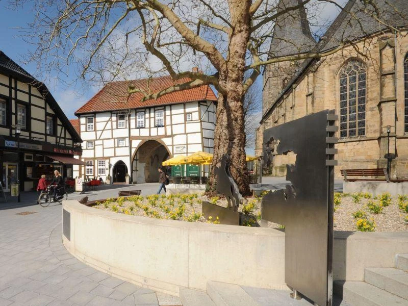 Ev. Stadtkirche Lengerich mit Römer / Friedensreiter Lengericher Stadtkirche mit modernem Römerdenkmal und historischem Fachwerkgebäude im Hintergrund.