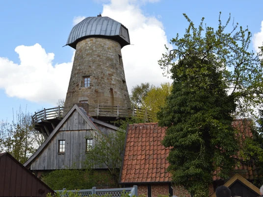 Levedags Mühle in Hörstel Historische Mühle in Hörstel mit steinernem Turm, umgeben von Backsteinhäusern und Bäumen.