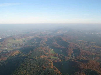 Rehm Ballooning: Genießen Sie die Aussicht! Ballonfahrt über eine hügelige, bewaldete Landschaft im Herbst, unter blauem Himmel.