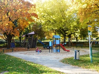 Spielplatz am Maspernplatz Spielplatz am Maspernplatz mit Rutsche, Klettergerüst, Wipptier, umgeben von herbstlichen Bäumen.