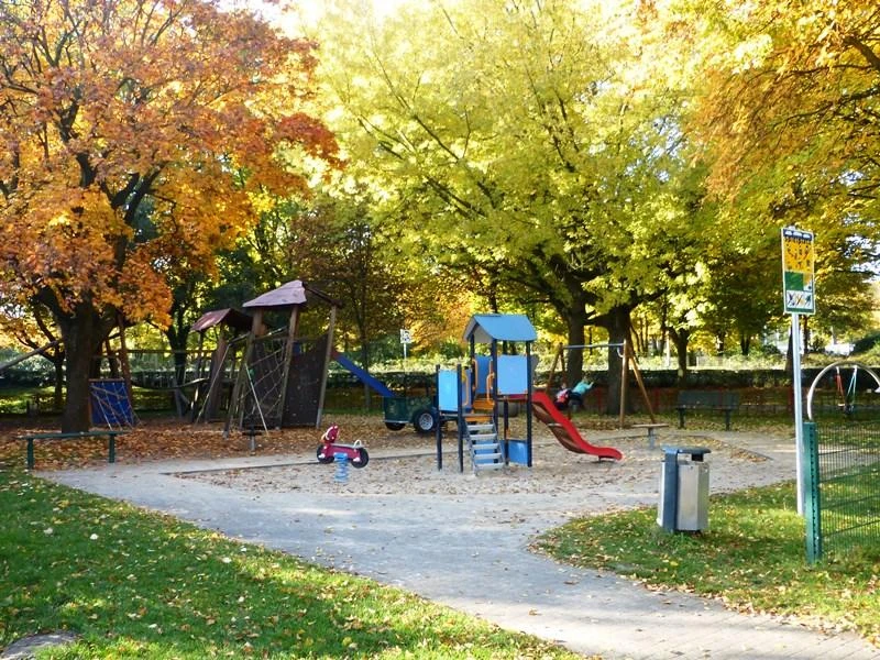 Spielplatz am Maspernplatz Spielplatz am Maspernplatz mit Rutsche, Klettergerüst, Wipptier, umgeben von herbstlichen Bäumen.