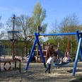 Spielplatz am Padersee Spielplatz am Padersee mit Klettergerüst, Schaukeln und Sandfläche, umgeben von Bäumen im Hintergrund.