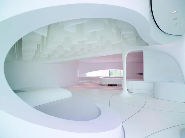 Leonardo glass cube Futuristisch gestalteter, weißer Raum mit organischen Linien und großzügigem Lichteinfall.