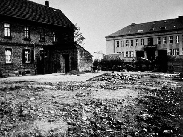Das dritte Rathaus, ab 1947 Historisches Rathaus von 1947, umgeben von Schutt und Trümmern in einer einfachen städtischen Umgebung.