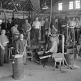 Eine Gruppe von Glasmachern in einer Werkstatt um 1930, ausgestattet mit traditionellen Werkzeugen.