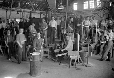 Glasmacher mit Arbeitsgerät um 1930 Eine Gruppe von Glasmachern in einer Werkstatt um 1930, ausgestattet mit traditionellen Werkzeugen.