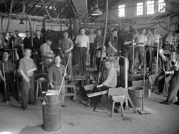 Glasmacher mit Arbeitsgerät um 1930 Eine Gruppe von Glasmachern in einer Werkstatt um 1930, ausgestattet mit traditionellen Werkzeugen.