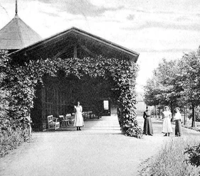 Caspar-Heinrich-Quelle Historisches Foto eines Pavillons mit Rankpflanzen, umgeben von Frauen in Kleidung des 19. Jahrhunderts.