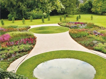 Piet-Oudolf-Garten Zwei runde Wasserflächen sind von üppigen Blumenbeeten und gepflegten Rasenflächen im Garten umgeben.