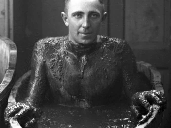 Kurgast im Moorbad um 1929 Mann um 1929 in einem hölzernen Moorbad, Kopf und Schultern frei, Rücken an eine Kante gelehnt.