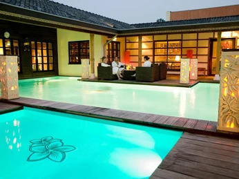 Bali Therme: Atrium Beleuchtetes Atrium der Bali Therme mit Pool und Menschen in entspannter Atmosphäre bei Abenddämmerung.