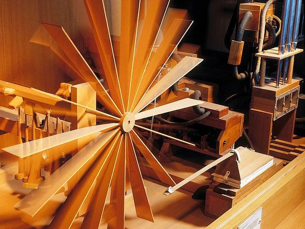 Windrad Ein hölzernes Windrad-Modell in einem Museum mit historischer Technik im Hintergrund.