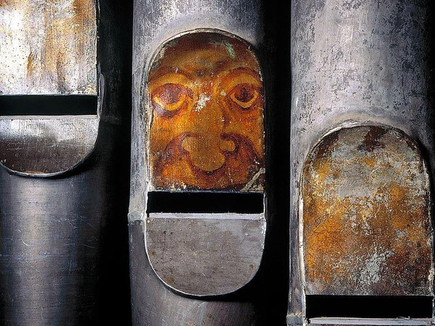 Orgelpfeifen mit kunstvoll verziertem Gesicht, das eine historische und kreative Atmosphäre ausstrahlt.