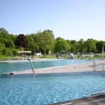 Rolandsbad Paderborn Ein modernes Freibad mit mehreren Schwimmbecken, grüner Umgebung und einem markanten Sprungturm.