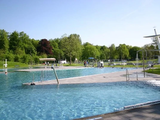Rolandsbad Paderborn Ein modernes Freibad mit mehreren Schwimmbecken, grüner Umgebung und einem markanten Sprungturm.